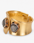 Sculptural gold cuff bracelet featuring a raw textured black stone surrounded by sparkling crystal accents.