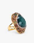 Emerald green statement ring featuring an organic stone surrounded by crystals and a Gold tone finish.