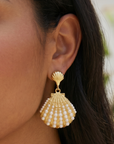 Gold shell dangle earrings featuring luminous pearl embellishments and coastal-inspired detailing by Sassy Jones.