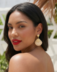 Gold shell dangle earrings featuring luminous pearl embellishments and coastal-inspired detailing by Sassy Jones.