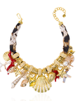 Statement charm necklace featuring pearl-studded shell pendants, coral accents, starfish charms, seashell details, pavé crystal elements, and gold-tone hardware by Sassy Jones.