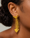 Gold statement earrings featuring elongated fishbone silhouettes with linked sections and crystal details.