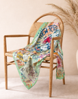 Travel inspired statement scarf featuring overlapping international passport stamps and decorative multicolor edging.
