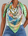 Multicolor oversized scarf featuring passport stamp illustrations in pink, blue, orange and green with a striped border.