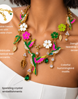 Gold statement necklace featuring three colorful hummingbirds, dangling crystal accents and delicate botanical charms.