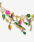 Sassy Jones Cherish Garden Necklace featuring green and pink hummingbirds surrounded by white, pink and green enamel flowers.