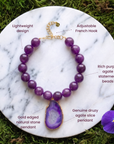 Purple gemstone statement necklace featuring round agate beads and a large gold-edged druzy pendant.