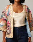 Front view of Fawna Jacquard Embroidered Jacket with colorful birds, open front silhouette, gold embroidery and blue lining.
Multicolor jacquard jacket featuring detailed birds and decorative gold embroidered borders along the front, sleeves and hem.
Fawna statement