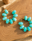 Teal statement hoop earrings featuring oversized marbled turquoise beads and gold-tone accents by Sassy Jones.