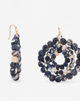 1. Close view of oversized black and white cloth bead dangle earrings with layered circular construction.