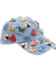 Light wash distressed denim ballcap featuring removable butterfly, ladybug, heart, and floral crystal brooch pins by Sassy Jones.