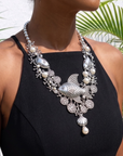 Antiqued silver statement necklace featuring sculpted fish, coral inspired branches, luminous pearl accents, shell details, and intricate ocean textures.