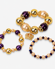 Three-piece Reign bracelet stack featuring champagne pearls, deep purple beads and gold accents.