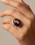 Purple statement ring featuring a polished stone, light contrasting centerpiece and Gold tone finish.