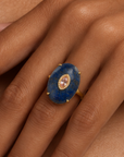 Navy statement ring featuring a smooth blue stone, petite lavender detail and Gold tone finish.