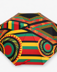 Sassy Jones patterned umbrella featuring a multicolor canopy with red, yellow, green and black detailing.