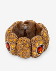 Amber statement bracelet featuring warm stone details, a faceted amber colored centerpiece and Gold tone finish.