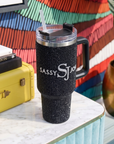 Sip, Sparkle & Slay Set featuring a black crystal sparkle tumbler, Maverick lip liner, Ibiza black crystal elephant stud earrings, and Ibiza black and gold bracelet stack.