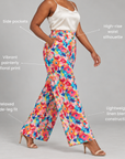 Woman wearing Sassy Jones Summer Garden high rise trousers with a vibrant multicolor floral pattern.