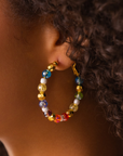 Colorful glass bead and pearl hoop earrings with gold accents designed for playful luxury styling