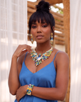 Statement peacock earrings featuring hand painted enamel feathers, sparkling crystal accents, gold shell studs, and colorful jewel toned detailing.