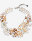 Mother of pearl floral statement necklace with sculptural petals and pearl clusters inspired by wisteria blossoms worn on a woman's neckline