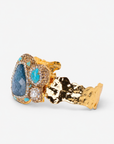 Blue statement cuff featuring an organic arrangement of blue green stones, creamy accents and Gold tone finish detailing.