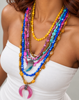 Multistrand Zuma statement necklace featuring rainbow shell beads, sparkling spear detail, and pink crescent pendant.
