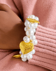 Model wearing Amora Pearl Heart Stretch Bracelet styled with pink sweater.