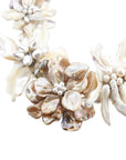 Mother of pearl floral statement necklace with sculptural petals and pearl clusters inspired by wisteria blossoms worn on a woman's neckline