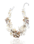 Mother of pearl floral statement necklace with sculptural petals and pearl clusters inspired by wisteria blossoms worn on a woman's neckline