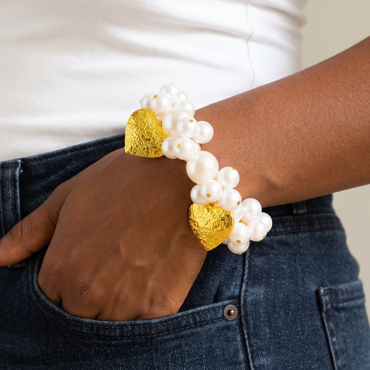 Amora bracelet shown on model with mixed size ivory pearls and two oversized textured heart charms.