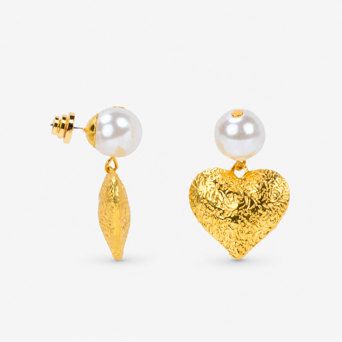 Close-up of Amora Pearl Heart Dangle on ear, gold and ivory details.      Sassy Jones Amora earrings featuring luminous pearl studs and dimensional heart shaped drops with ornate detailing.
