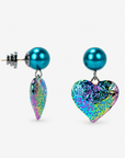 Sassy Jones Amora Rainbow Teal earrings featuring sculptural heart pendants in teal, pink, green, purple and gold hues.
Colorful heart statement earrings with glossy teal glass pearl studs and textured iridescent rainbow drops.