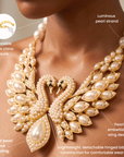 Luxury statement bib necklace featuring mirrored swans surrounded by radiant crystals and dimensional ivory pearl feathers.