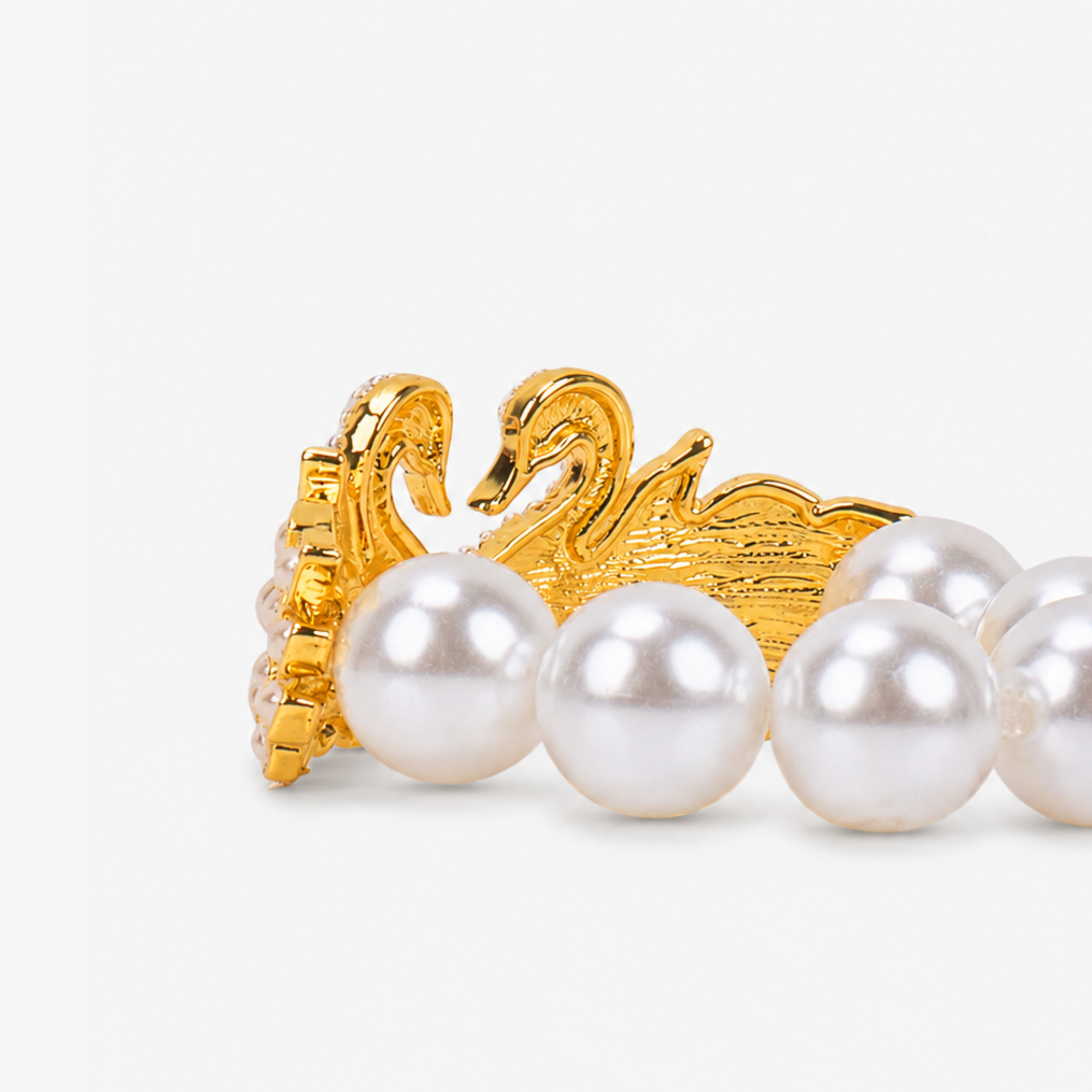 Gold swan statement bracelet designed with mirrored crystal swans, layered pearl wings, and oversized ivory pearl beads