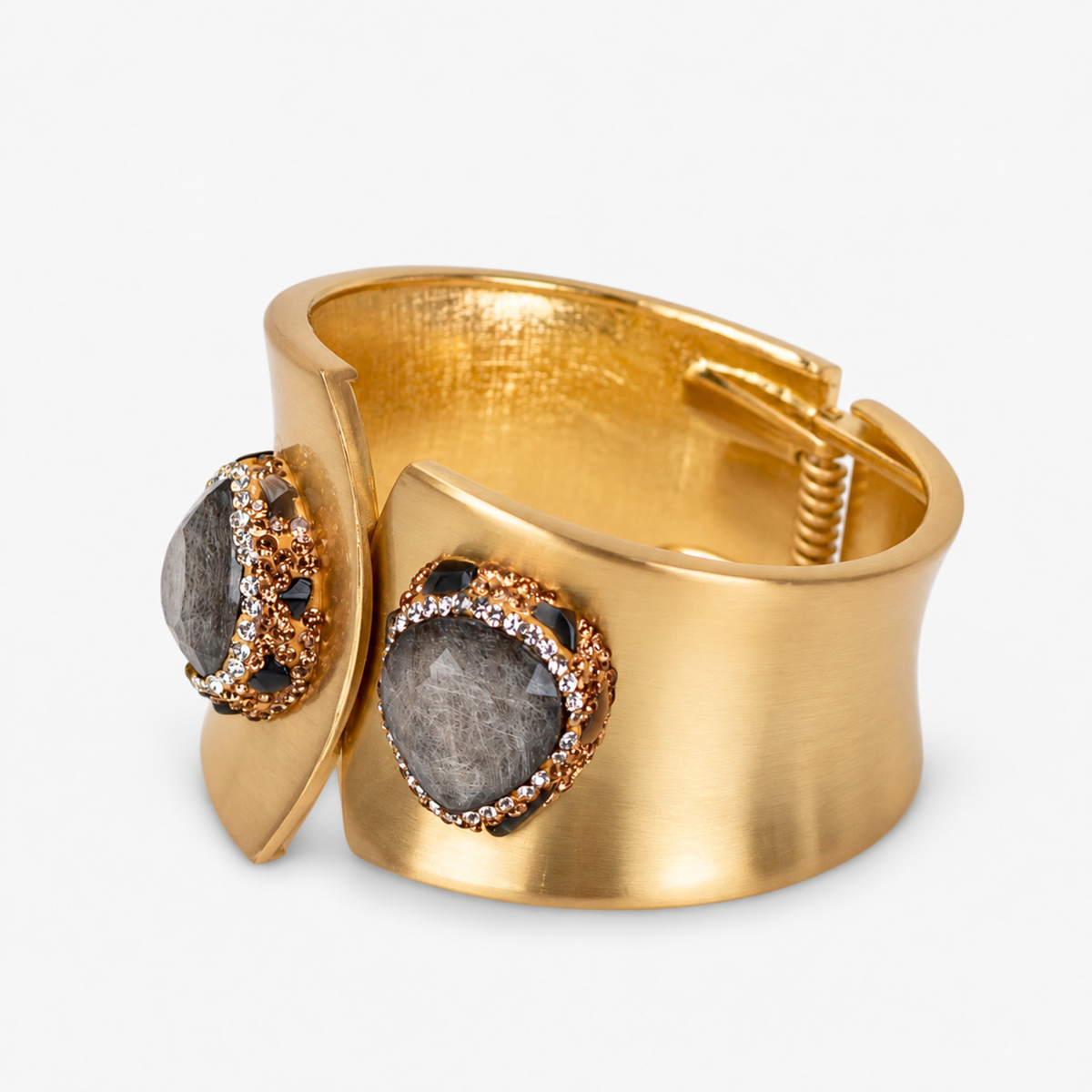 Sculptural gold cuff bracelet featuring a raw textured black stone surrounded by sparkling crystal accents.
