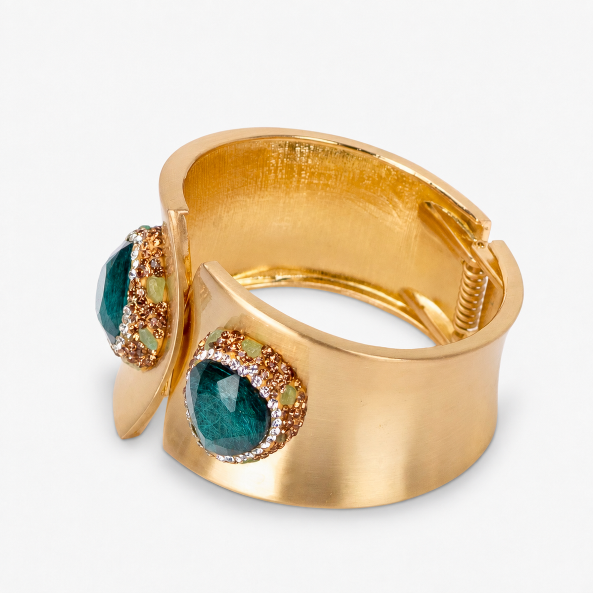 Wide gold cuff bracelet featuring oversized emerald green stones surrounded by sparkling crystal accents.