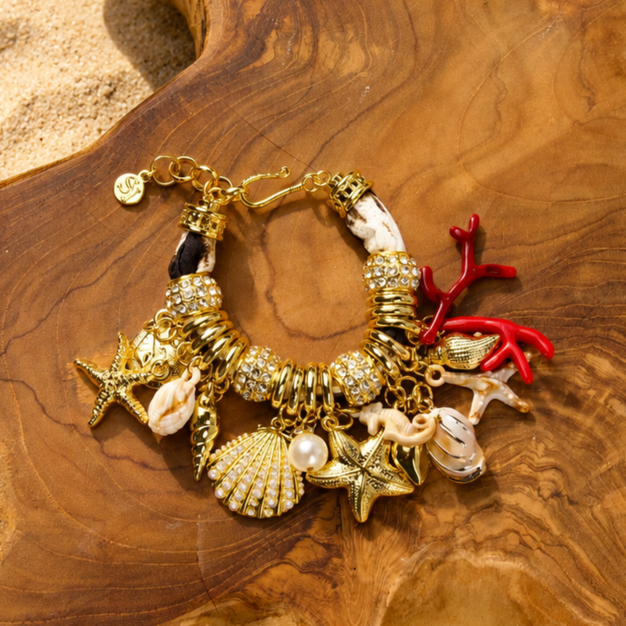Statement charm bracelet featuring coral accents, starfish charms, seashell details, pearl embellishments, pavé crystal accents, and gold-tone hardware by Sassy Jones.