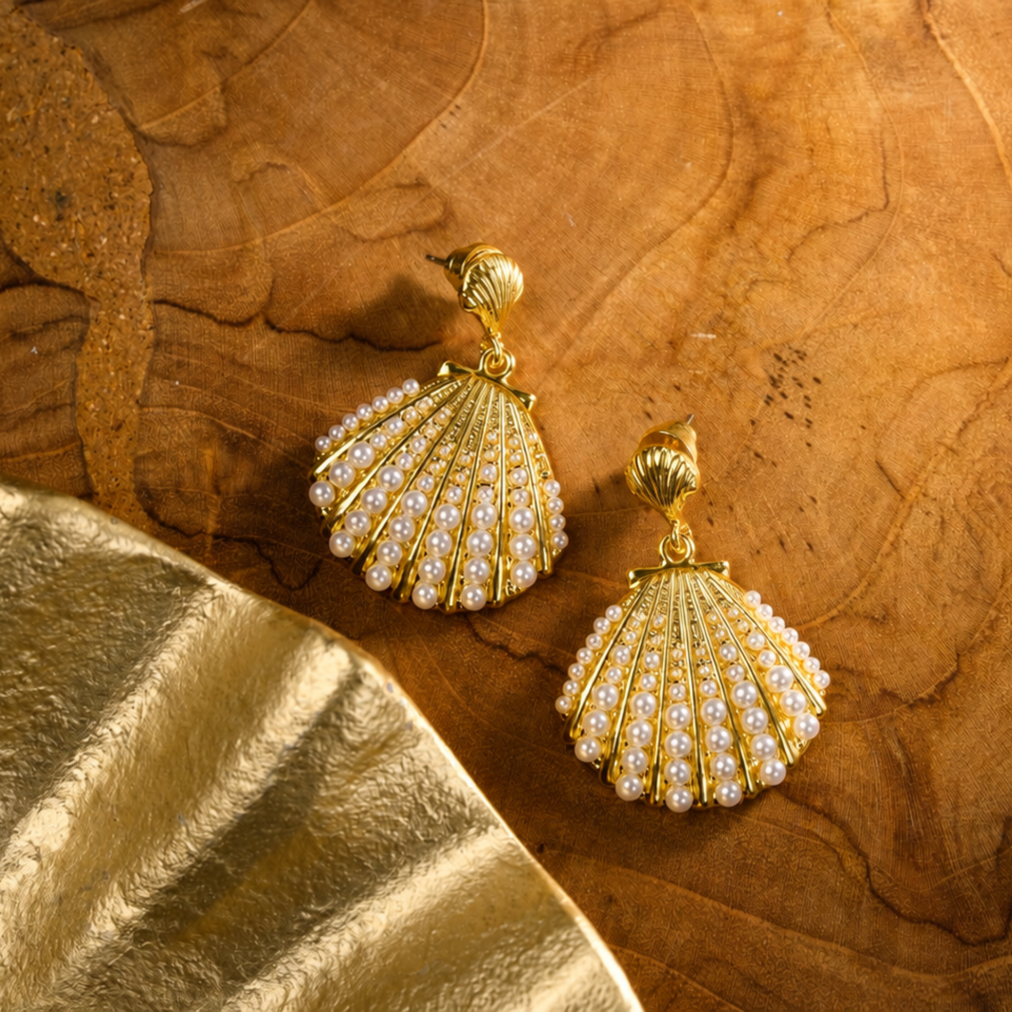 Gold shell dangle earrings featuring luminous pearl embellishments and coastal-inspired detailing by Sassy Jones.