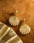 Gold shell dangle earrings featuring luminous pearl embellishments and coastal-inspired detailing by Sassy Jones.