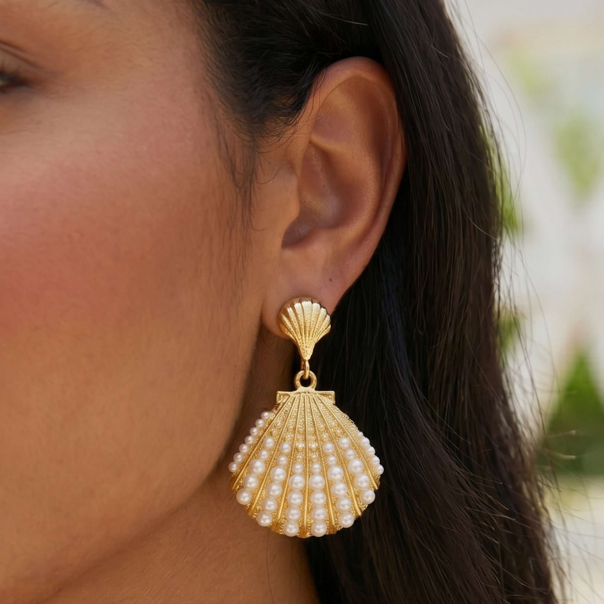 Gold shell dangle earrings featuring luminous pearl embellishments and coastal-inspired detailing by Sassy Jones.