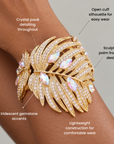 Gold statement cuff bracelet designed as a dimensional palm frond with sparkling crystal detailing.
