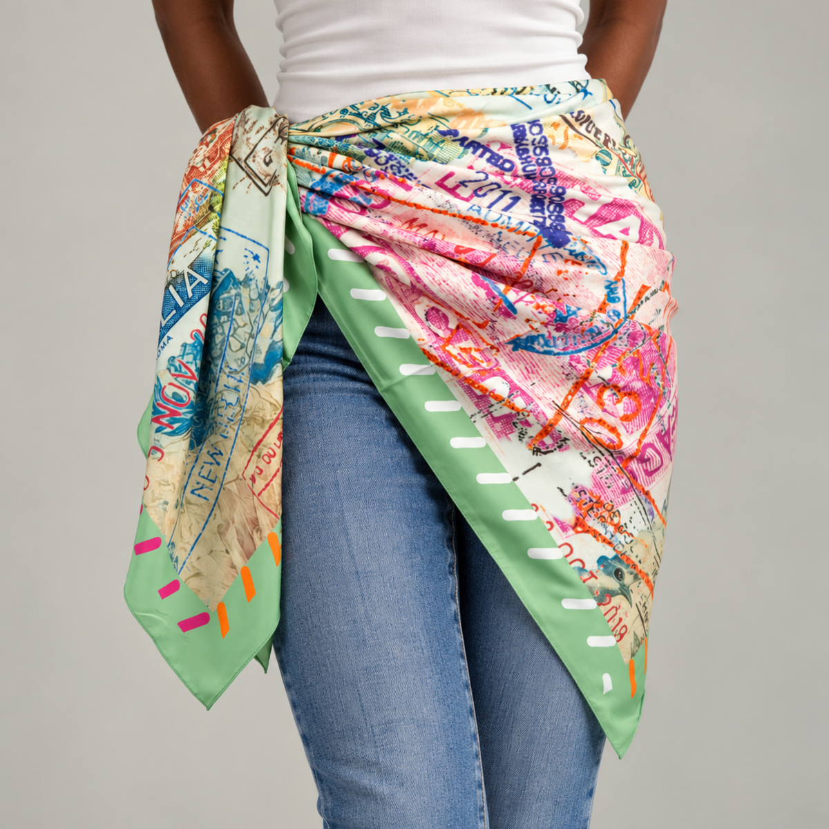 Charis Jetset Passport Stamp Scarf displayed flat featuring a vibrant collage of global travel imagery and a green striped border.