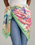Charis Jetset Passport Stamp Scarf displayed flat featuring a vibrant collage of global travel imagery and a green striped border.