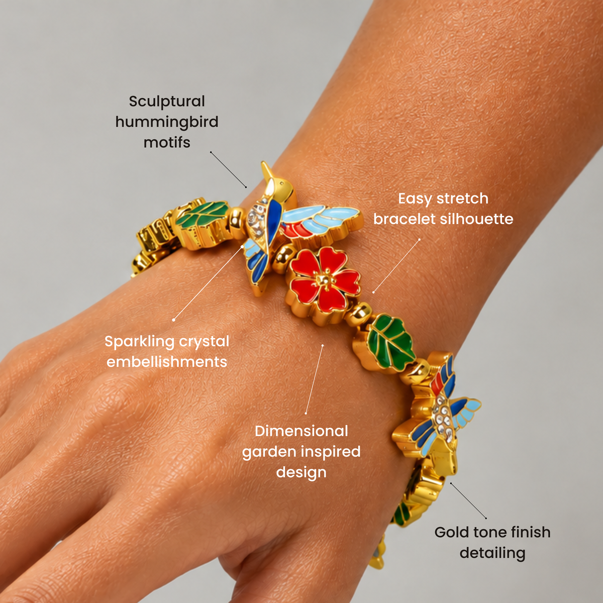 Gold colored stretch bracelet featuring sculptural hummingbird motifs, green enamel leaves and a coral flower centerpiece.