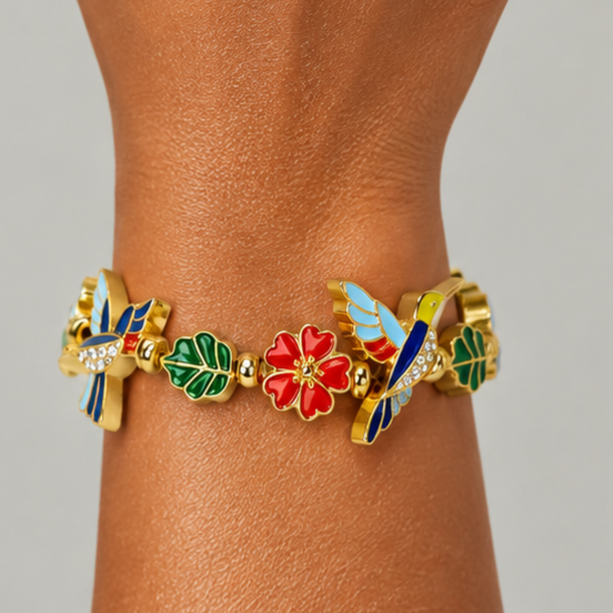 Nature inspired statement bracelet featuring dimensional hummingbirds, botanical leaves and vibrant floral embellishments.