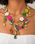 Whimsical garden inspired necklace featuring multicolor hummingbird pendants, gold leaves and decorative flower charms.