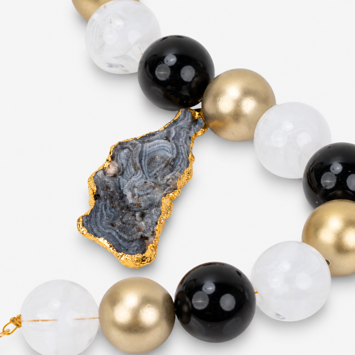 Black and gold statement necklace featuring chunky round beads and an organic raw agate centerpiece.