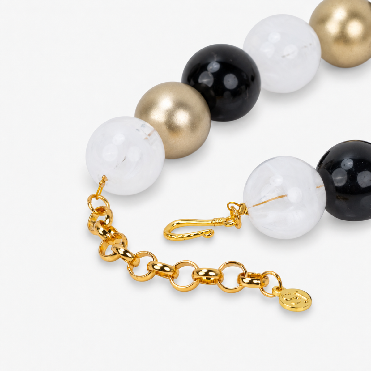 Close-up of Chrysallis chunky bead necklace with black, clear, and brushed gold beads and a natural stone pendant.

Black gold and clear chunky necklace featuring an organic agate centerpiece and adjustable chain closure.